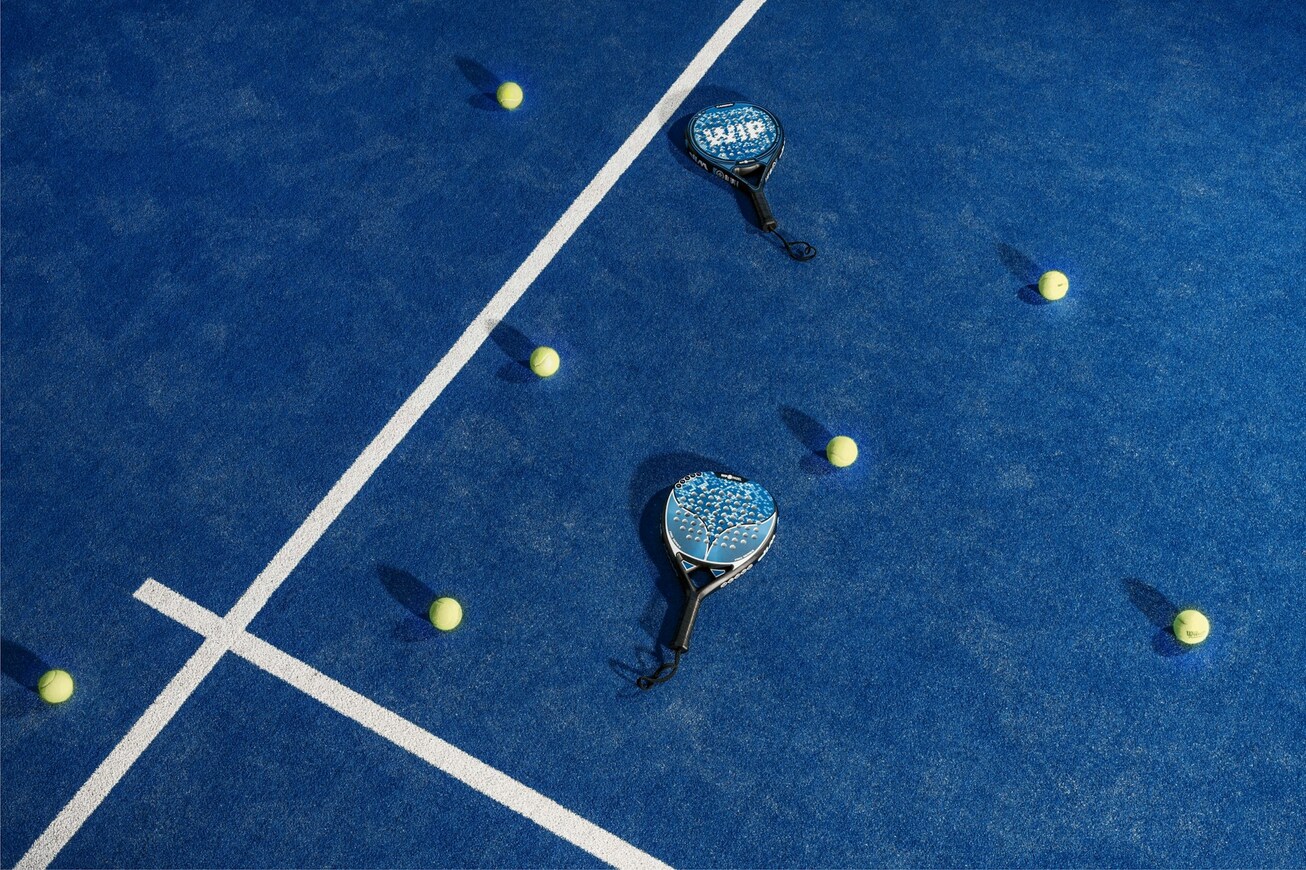 Foto van padelspullen die neerliggen op het padelveld.